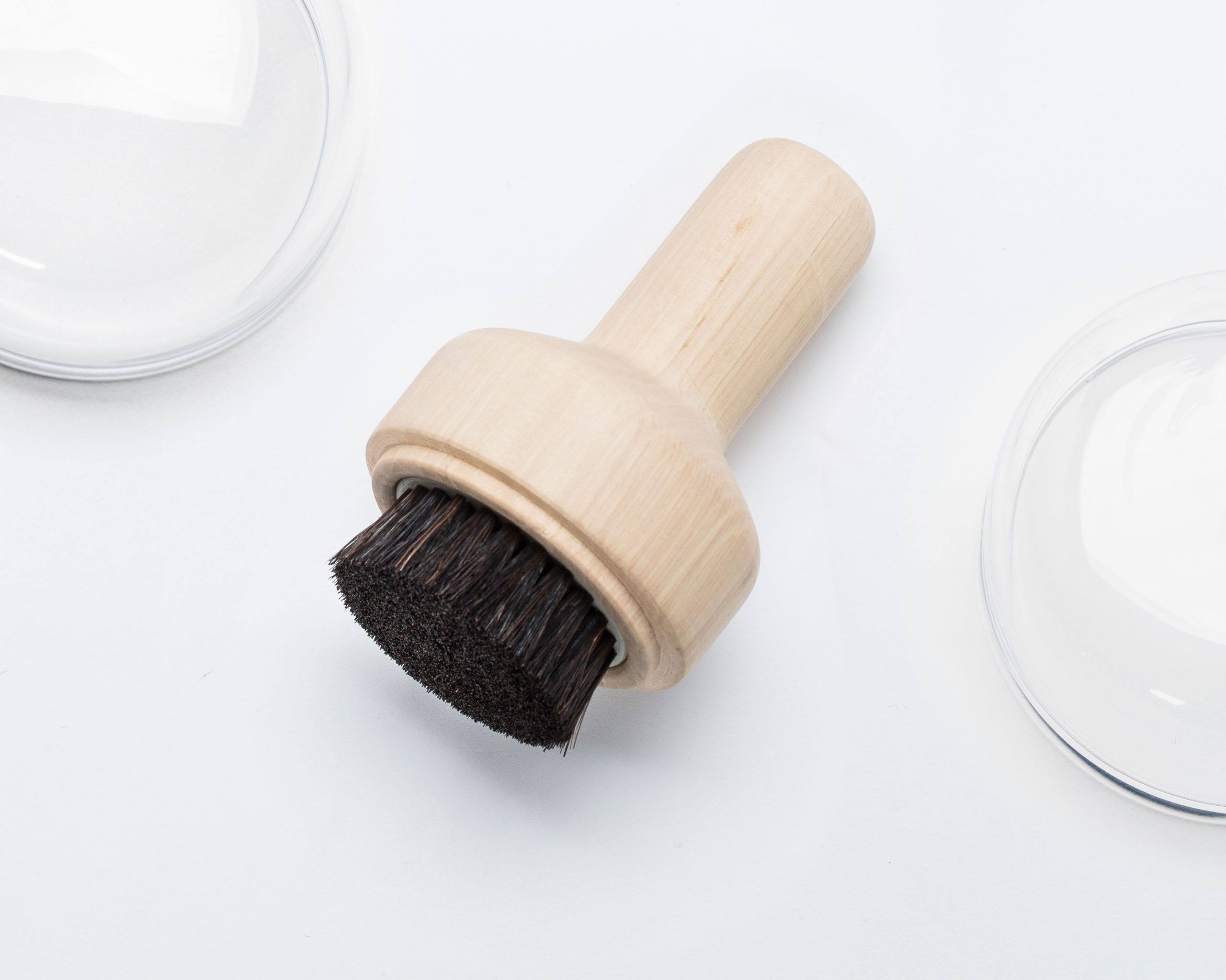 A shoe brush made of wood and natural bristles with an extended handle.