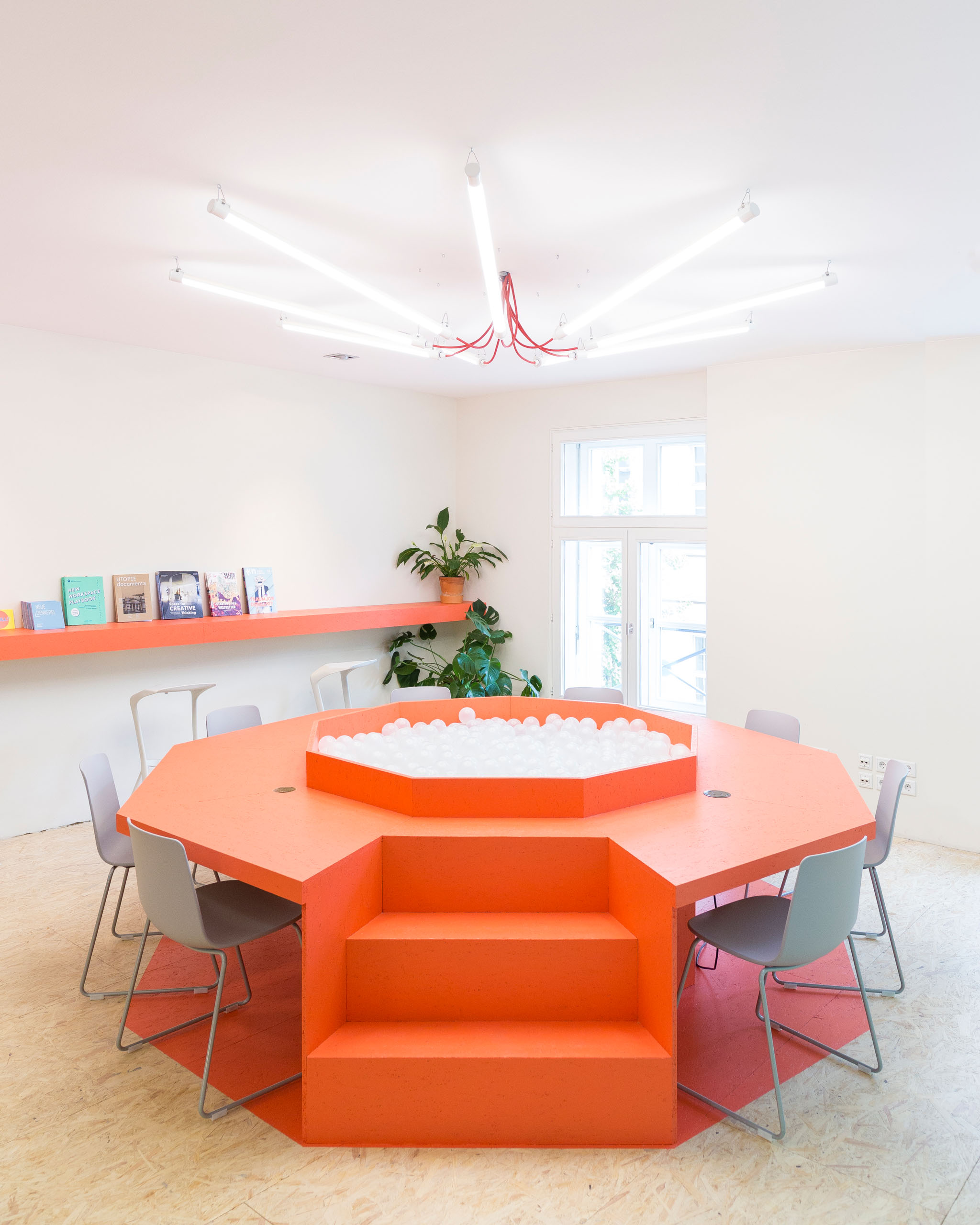 The interior of the Neue Denkerei coworking space. In the middle of the room there is a big bright orange desk.